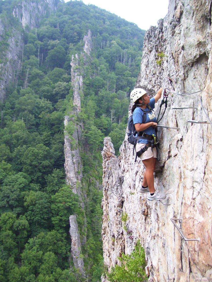 Climber on via ferrata clipped to steel cable with helmet and harness